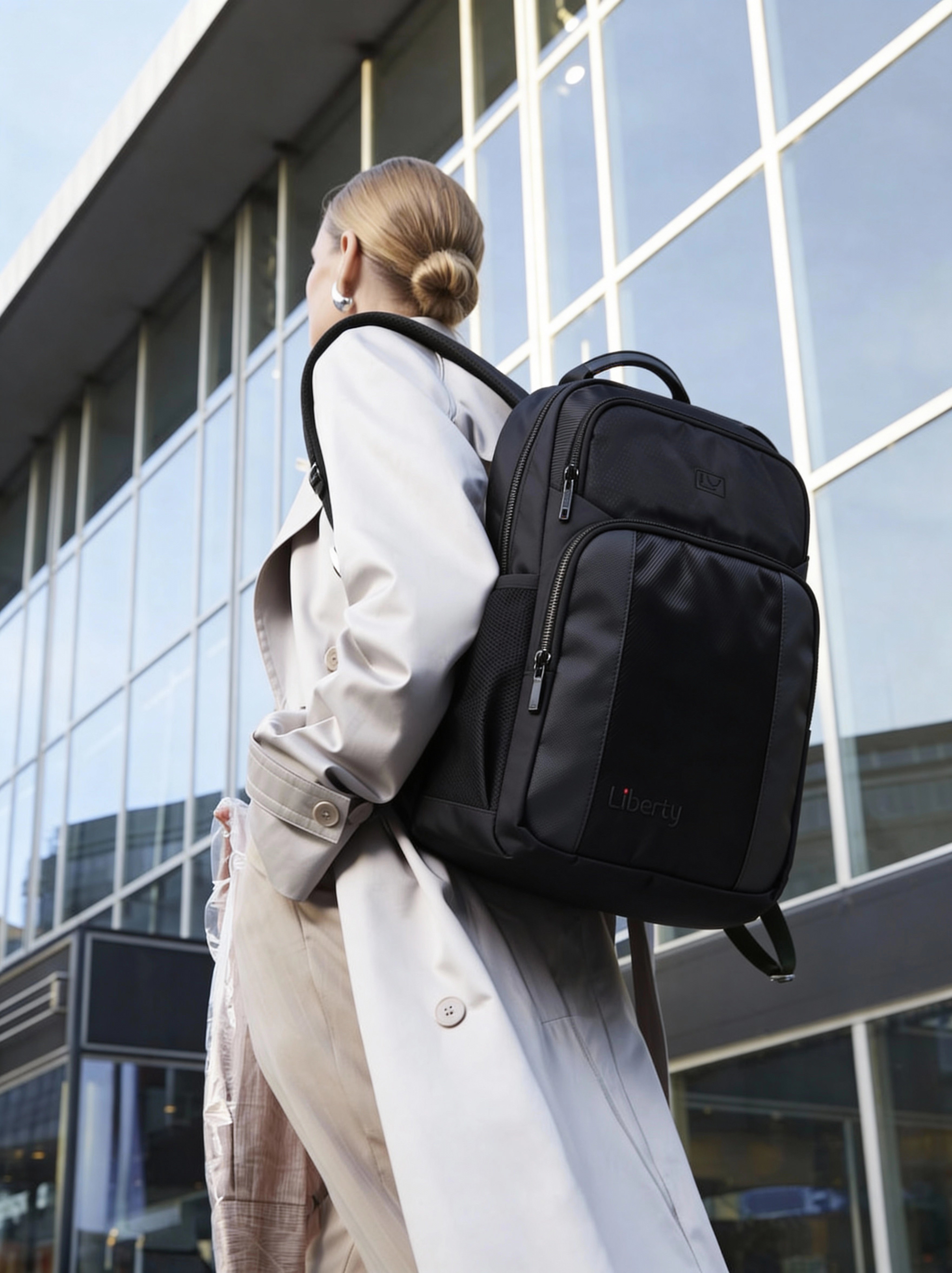Person wearing a black backpack in front of a modern building