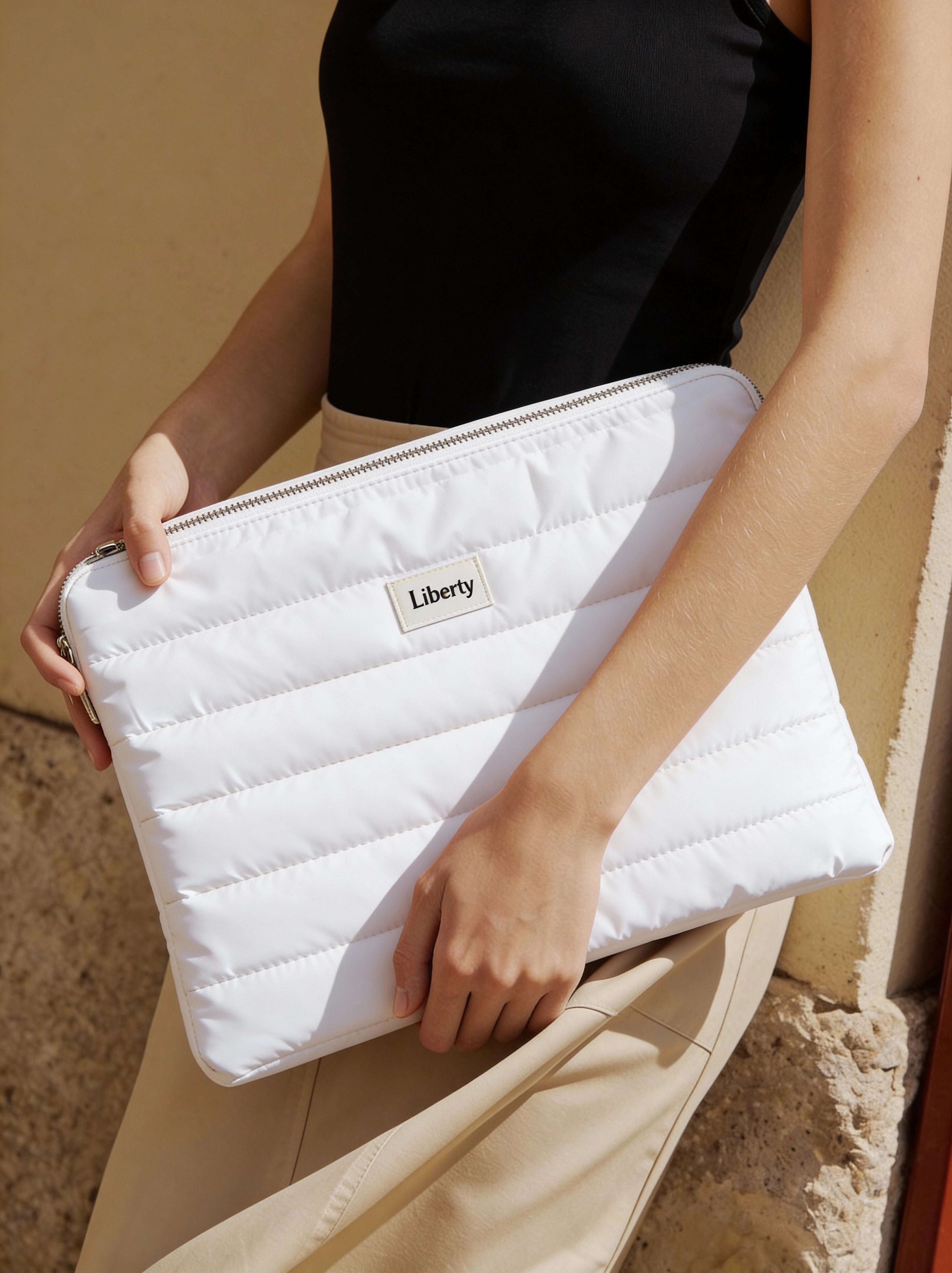 White quilted clutch held by a person with 'Liberty' branding.
